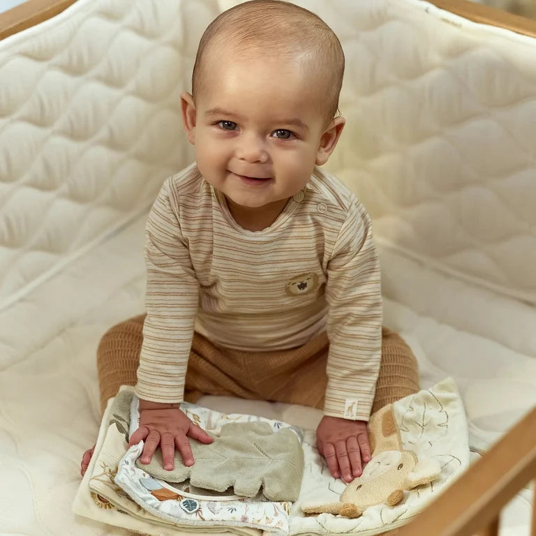 Bébé souriant assis sur une couverture dans un lit