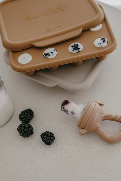 Tétine grignoteuse en silicone caramel avec anneau de dentition, présentée avec des mûres